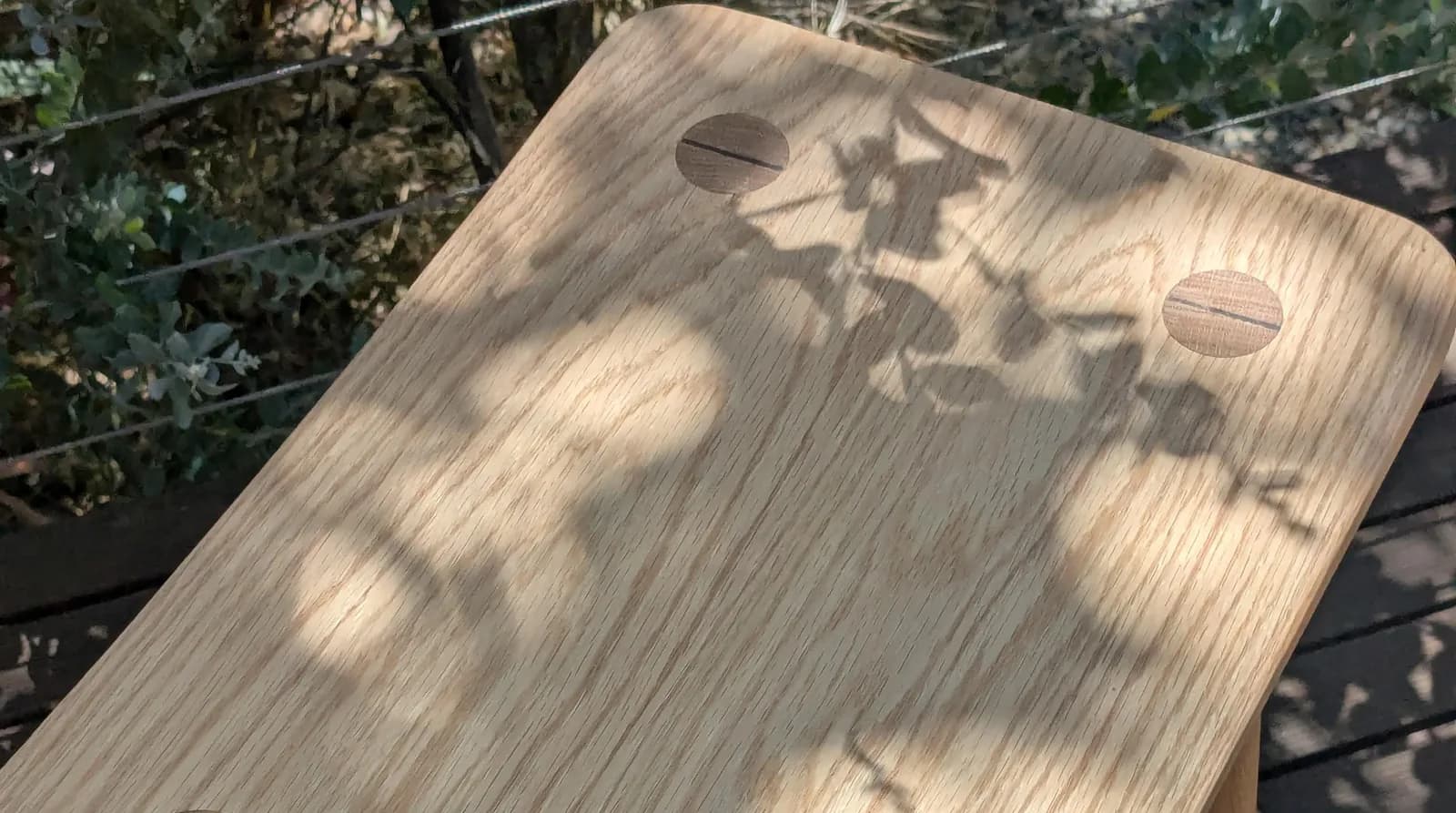 A solid oak stool showing wedged through-tenon joinery in the seat