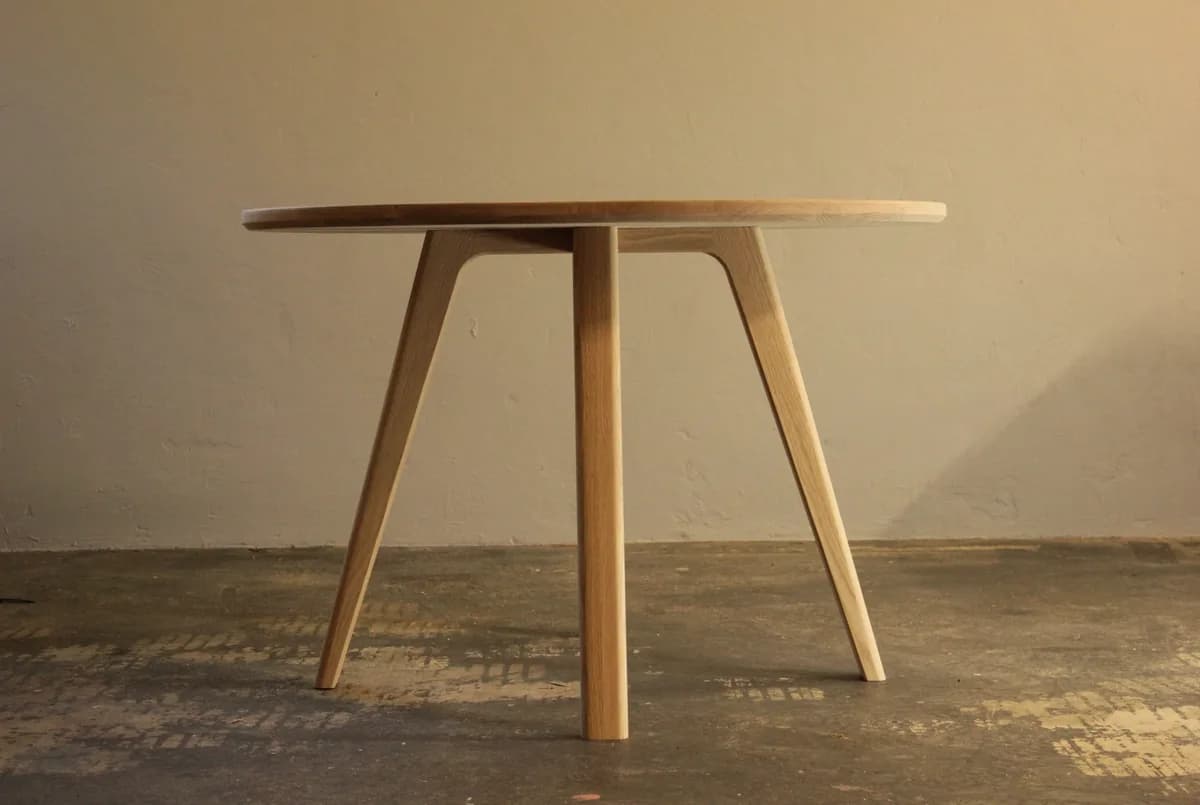 A round solid timber dining table with tapered splayed legs